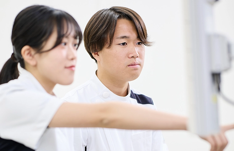 画像：制服をきた男女が器具を学んでいるところ。